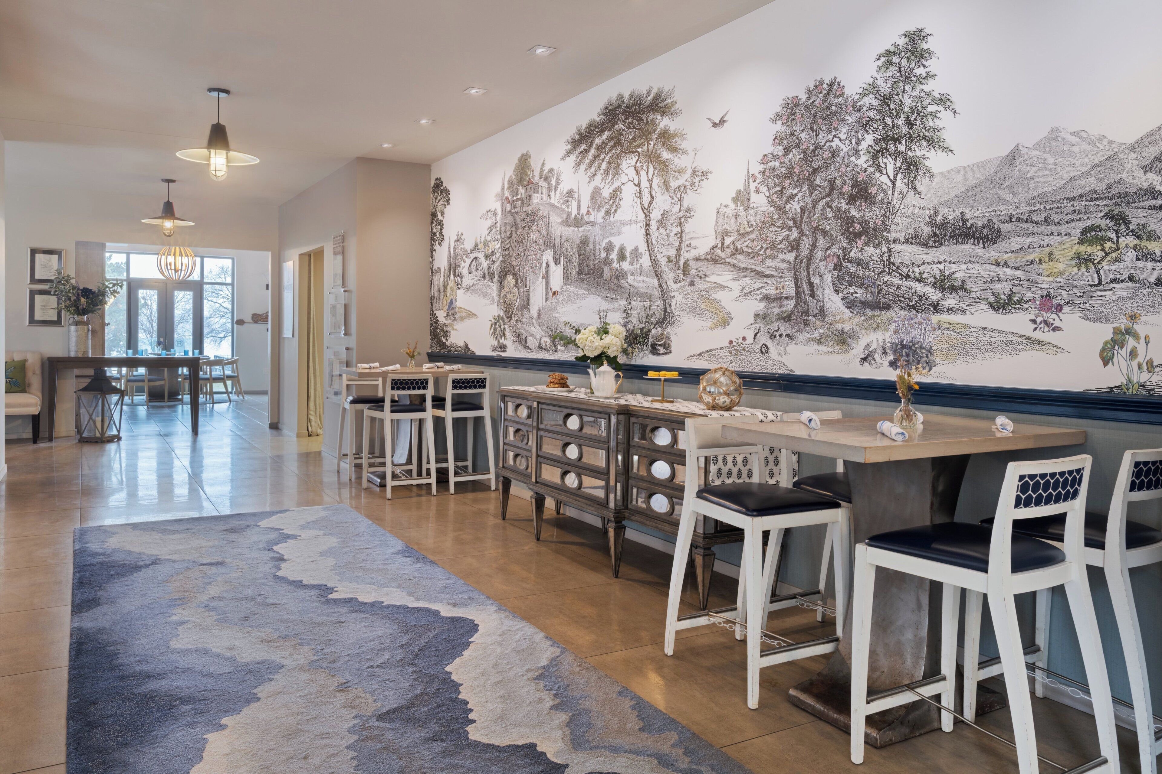 Un comedor con un mural, taburetes de bar y una barra de madera.