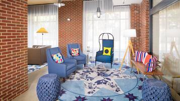 Relax in a cozy lounge area with comfortable seating options and a brick accent wall.