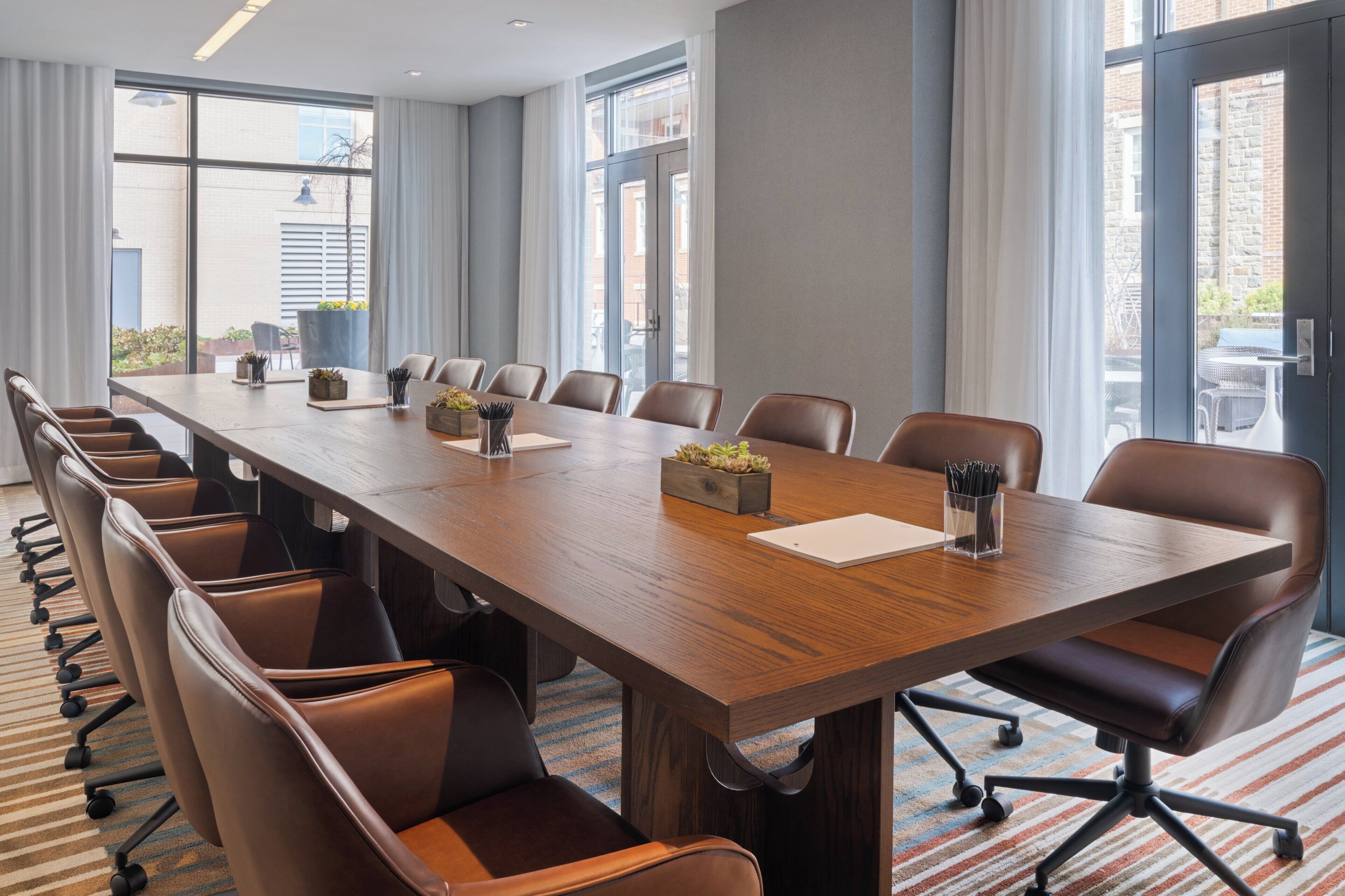 Une salle de conférence avec une longue table, des chaises et une vue dégagée grâce à de grandes fenêtres.