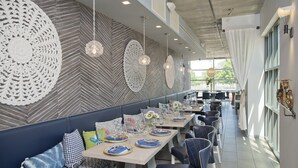 Ein modernes Restaurant mit einer langen Theke, blauen Sitzmöbeln und Wandkunst.