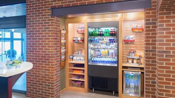 A corner vending area with a refrigerator stocked with beverages and snacks, a small cooler with drinks, and a display of bottled water.