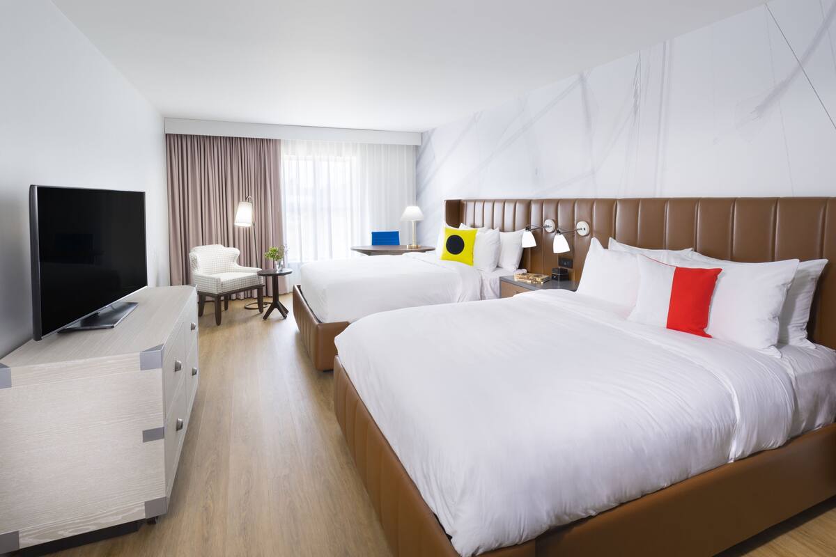 Ett hotellrum med en stor säng, en TV, ett skrivbord och en stol.