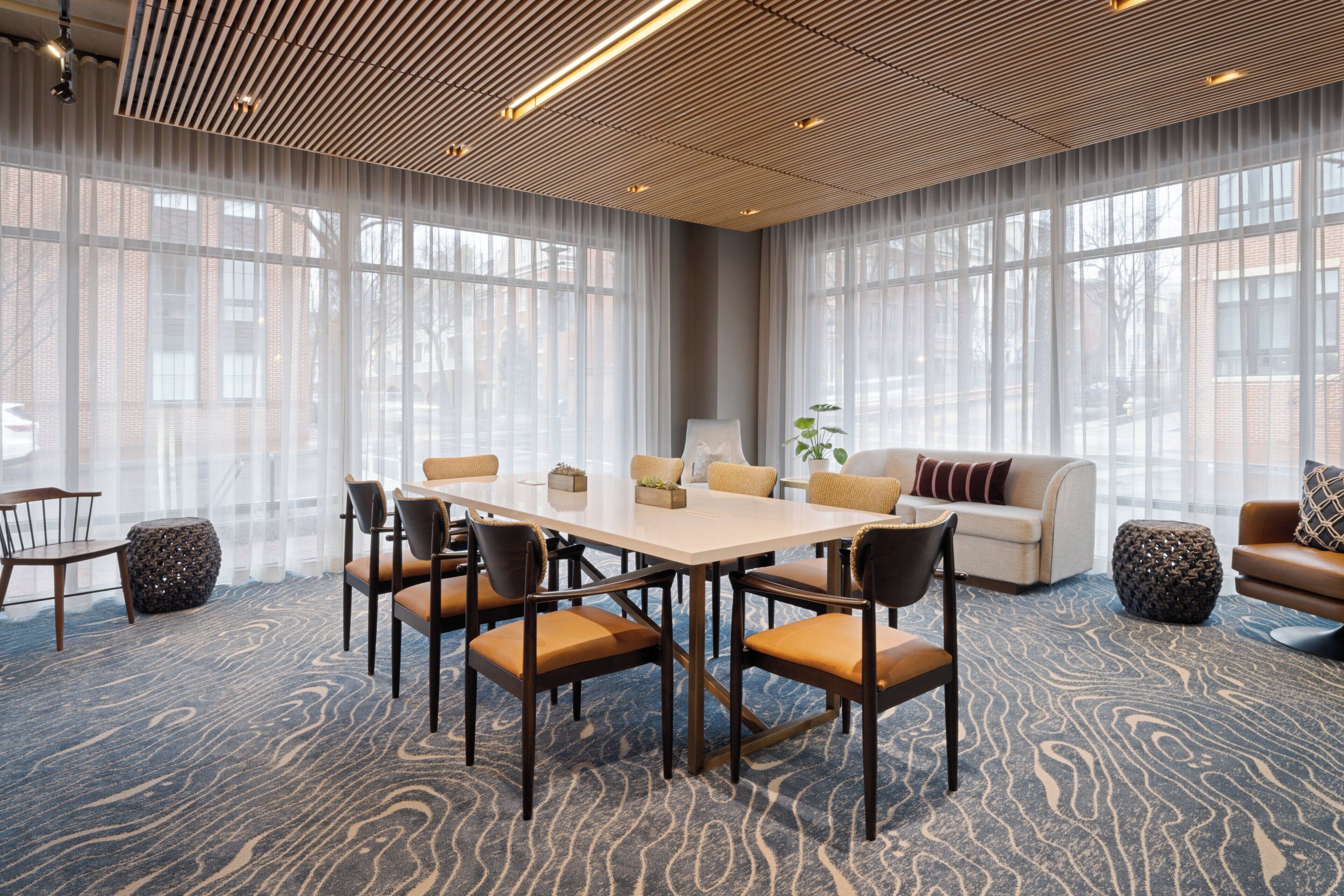 A conference room with a large table, chairs, a sofa, and a patterned carpet.