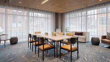 A conference room with a large table, chairs, a sofa, and a patterned carpet.