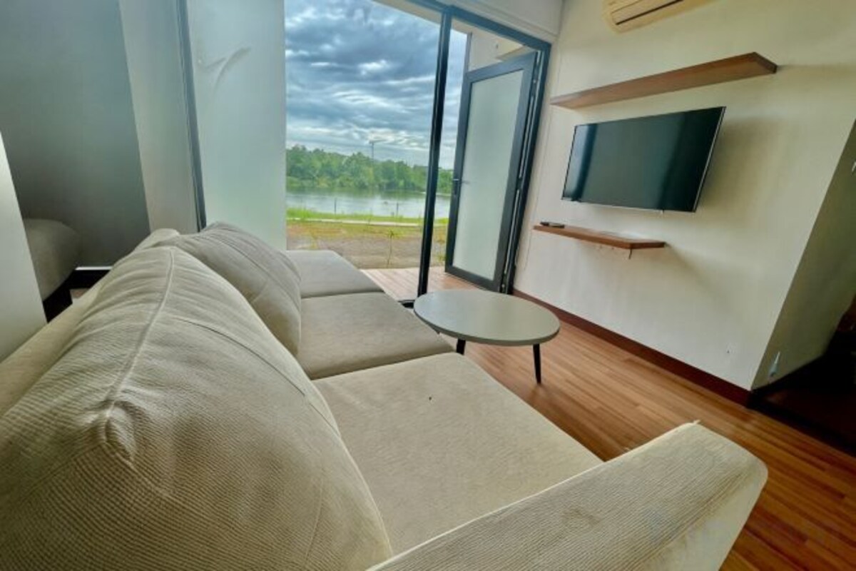 A modern living room with a sofa, a small table, and a TV mounted on the wall.