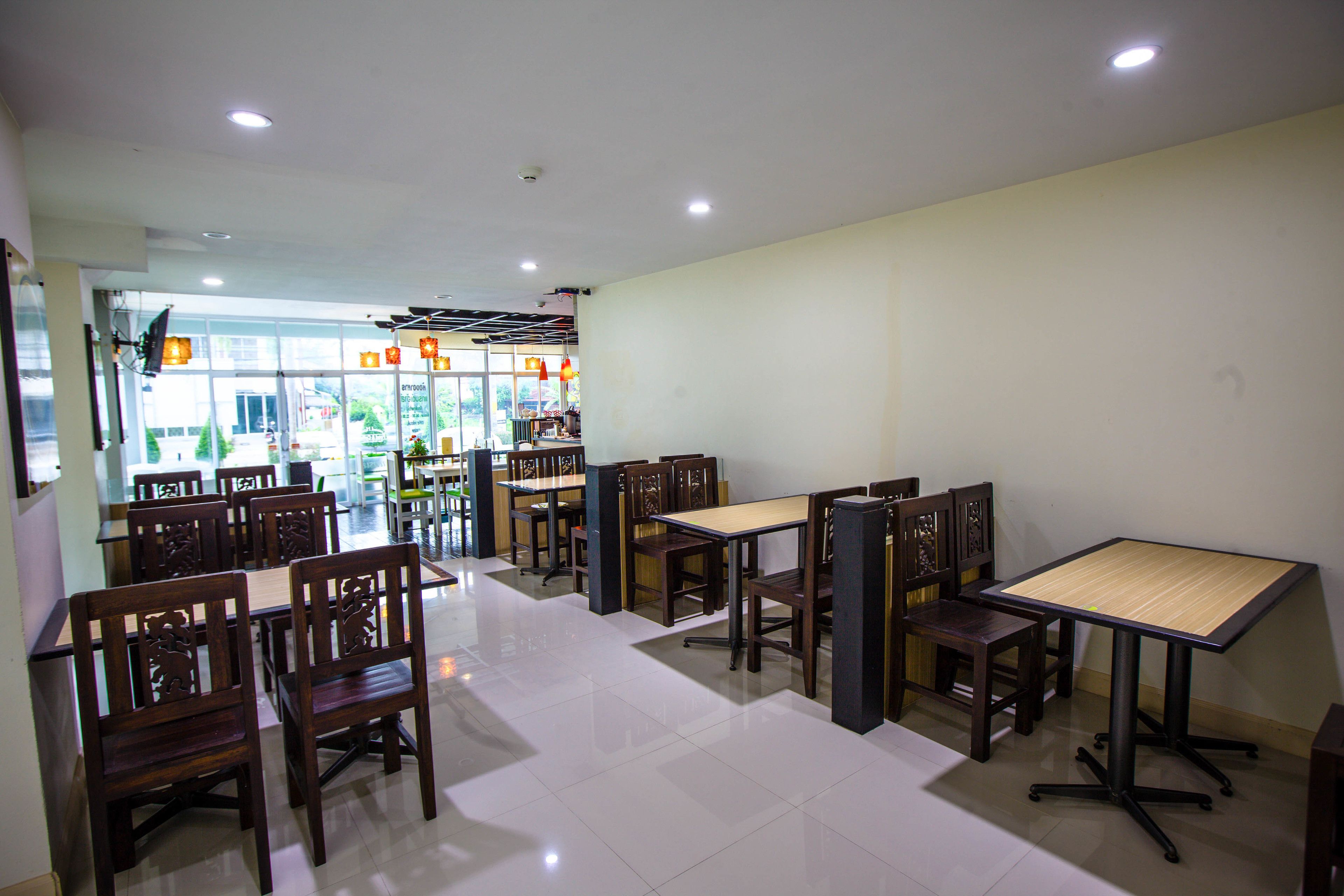 A restaurant with wooden tables and chairs, a tiled floor, and a view through large windows.