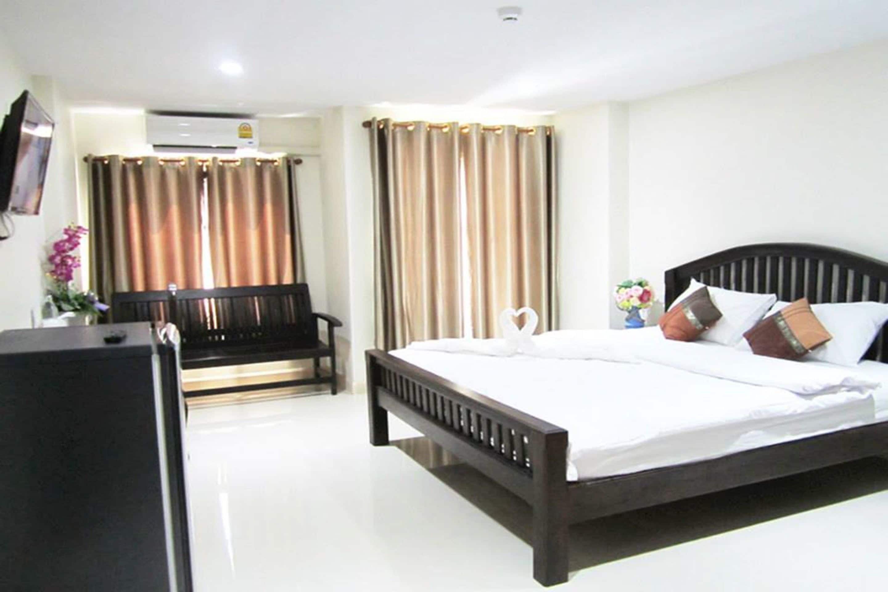 A hotel room with a large bed, a desk, and a chair.