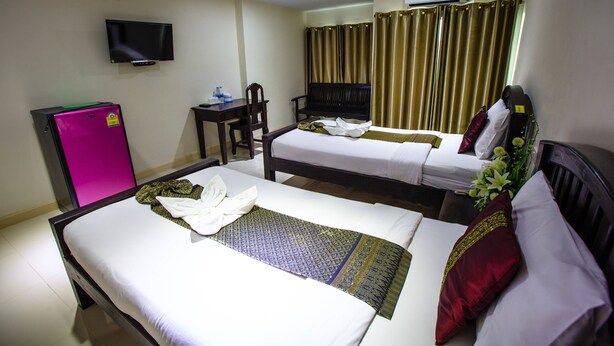 Een hotelkamer met twee bedden, een bureau, een stoel, een televisie en gordijnen.