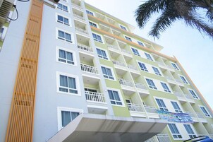 A multi-story hotel with balconies, a flat roof, and a signboard.