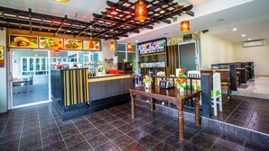 Een restaurant met een toonbank, zitgedeelte en een plafondventilator.