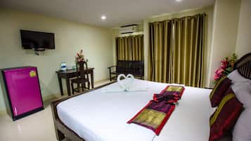 A hotel room with a bed, a desk, a TV, and an air conditioner.