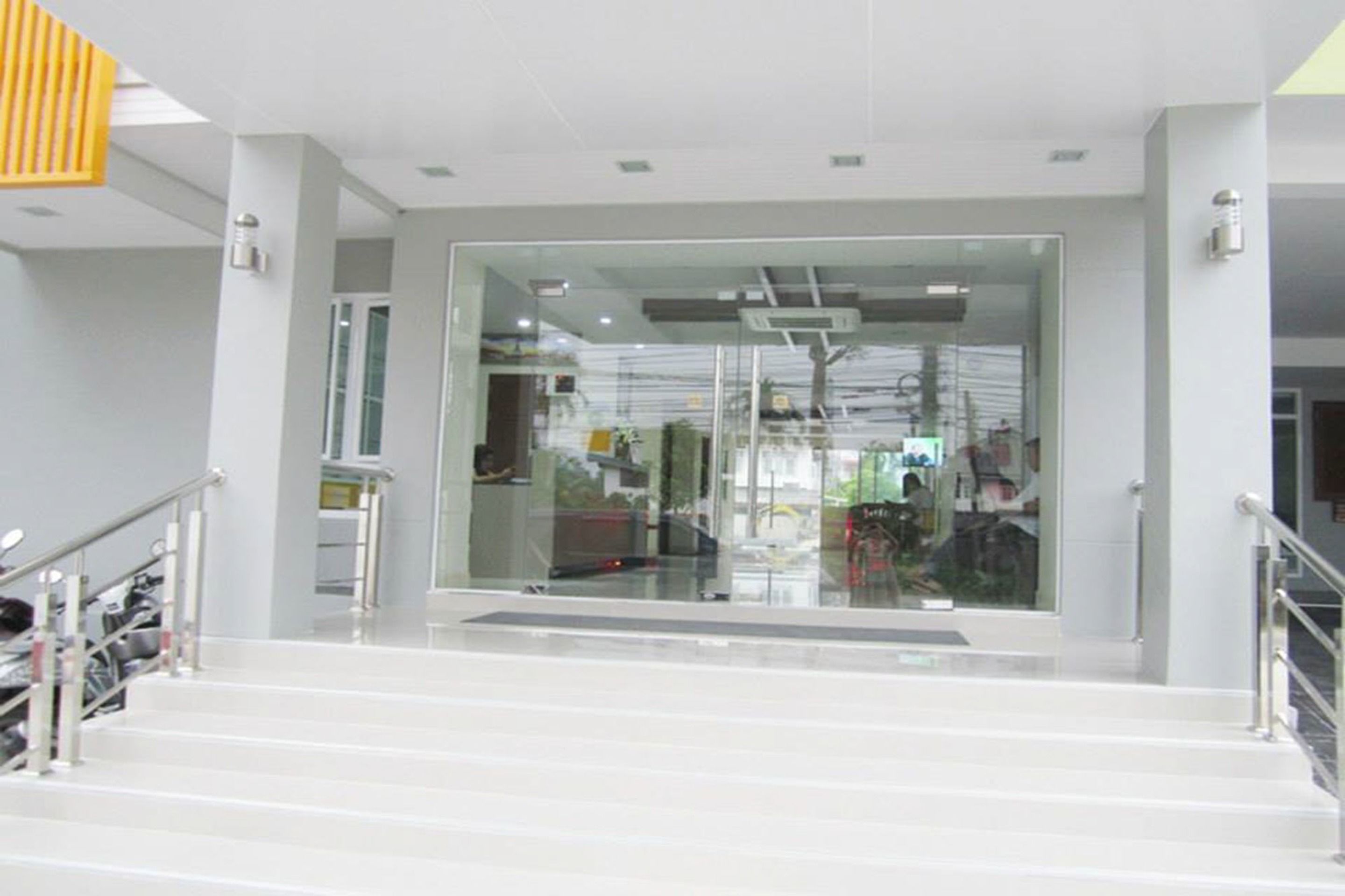 A modern interior with a glass door entrance, metal railings, and a staircase leading to an upper level.