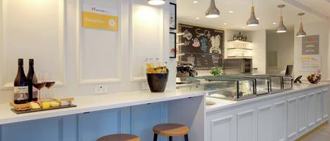 A reception area with a sign indicating 'Reception', a counter with bottles and glasses, and three wooden stools.