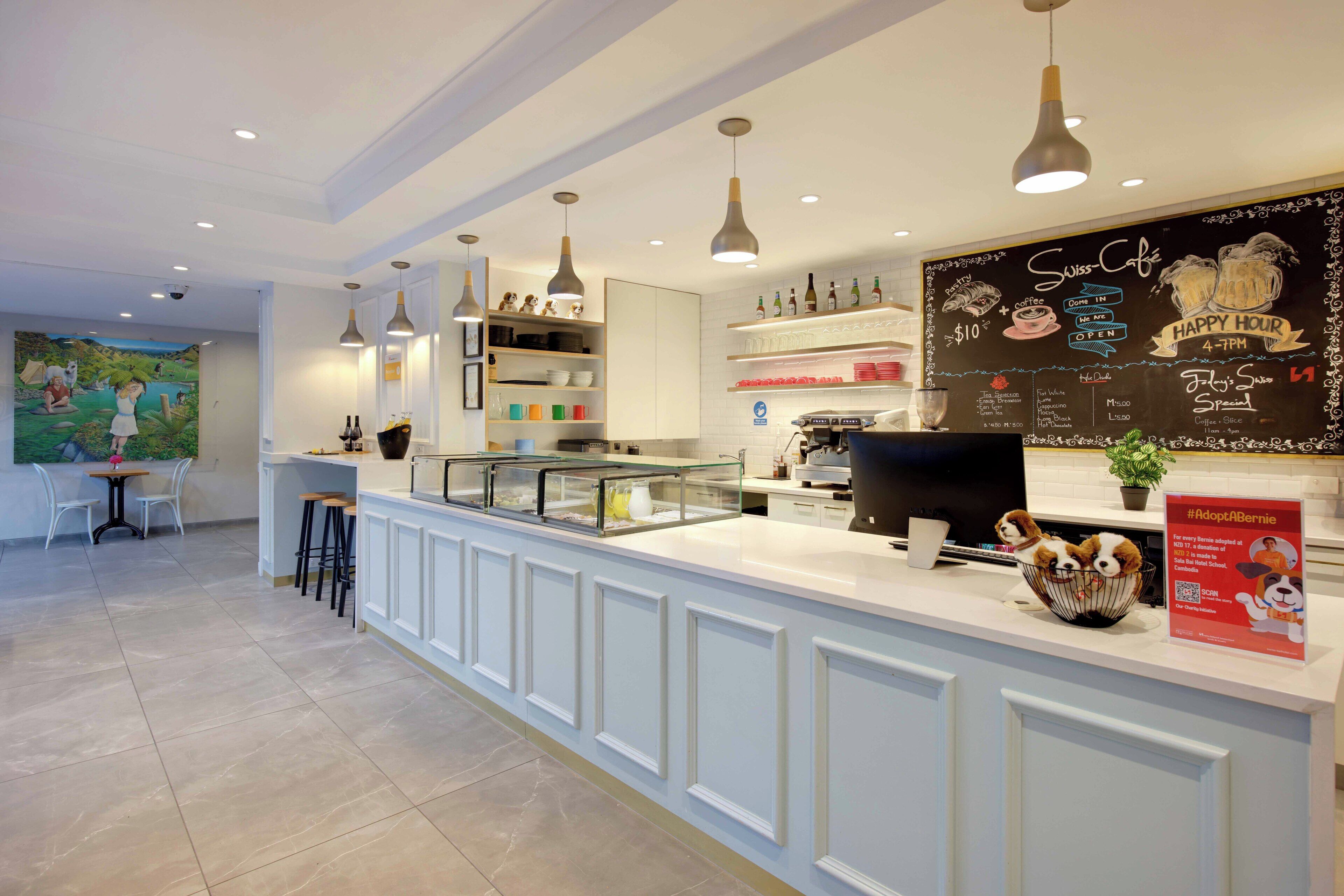 A modern cafe with a chalkboard menu, bar stools, and a decorative dog bowl on the counter.