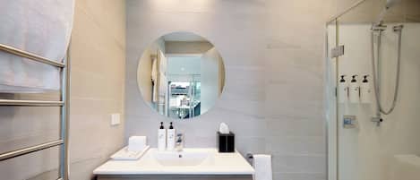 A modern bathroom with a large mirror, a sink, and a shower.