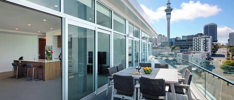 Quarto de hotel moderno com varanda, janelas amplas e vista para o horizonte urbano, incluindo uma torre.