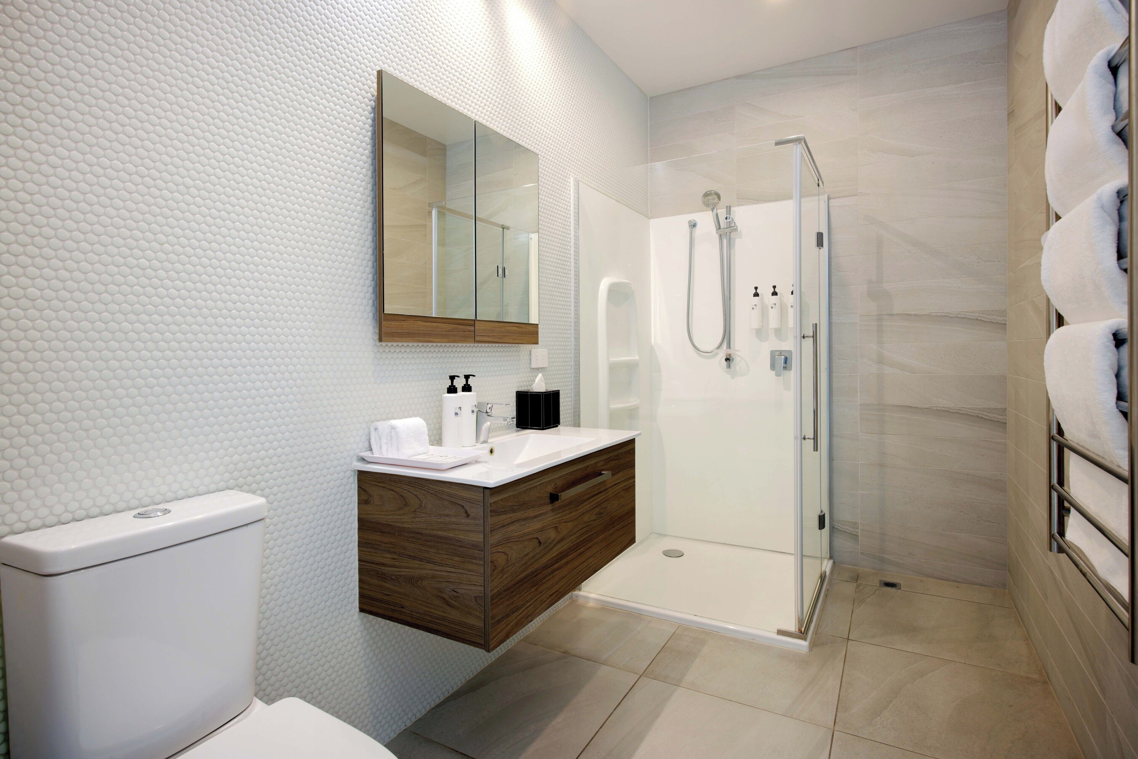 A modern bathroom with a toilet, vanity, and shower.