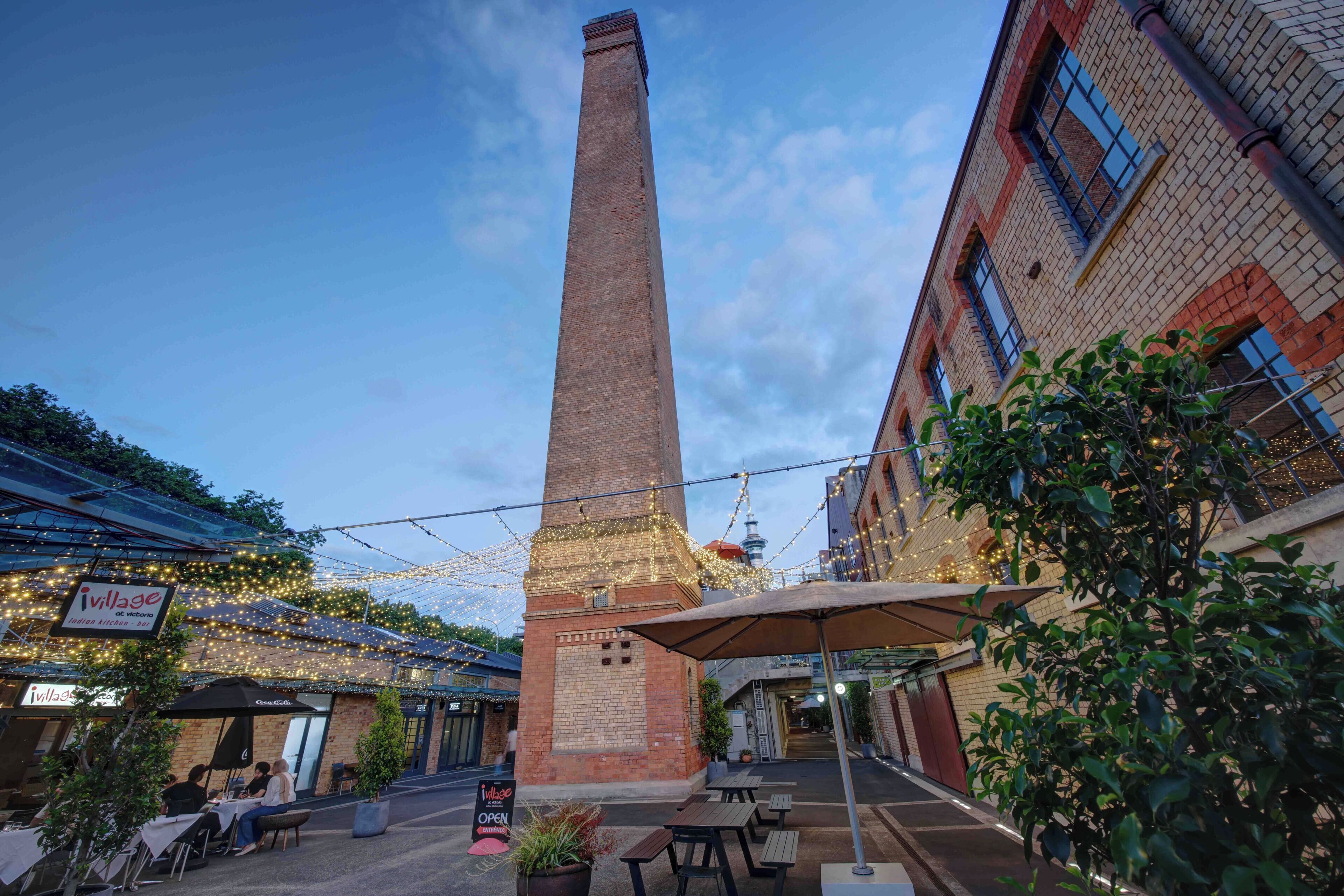 A brick tower with a flat top, surrounded by outdoor seating and string lights.