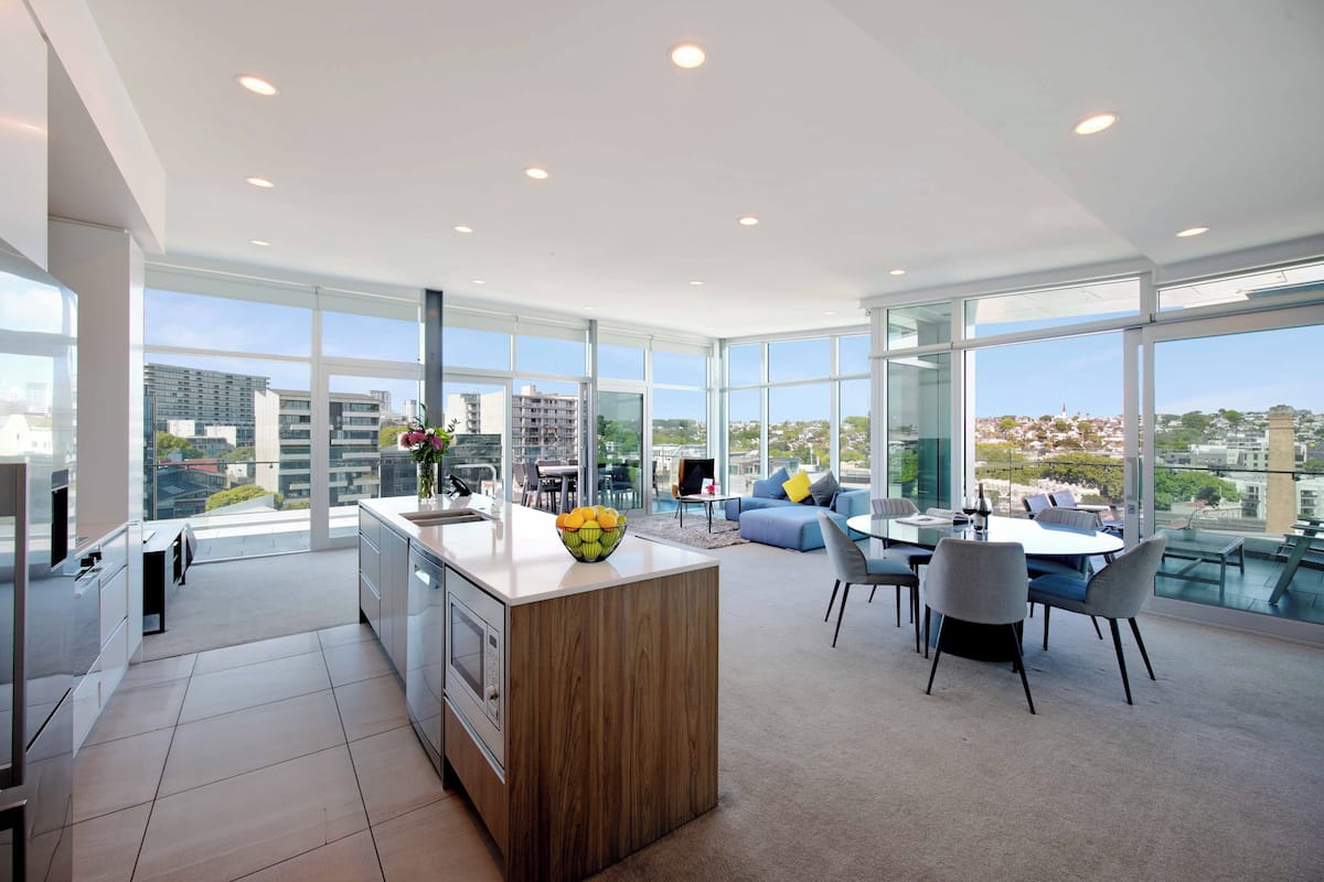 Eine moderne Wohnung mit Küche, Essbereich und Wohnzimmer mit großen Fenstern und Blick auf die Stadt.