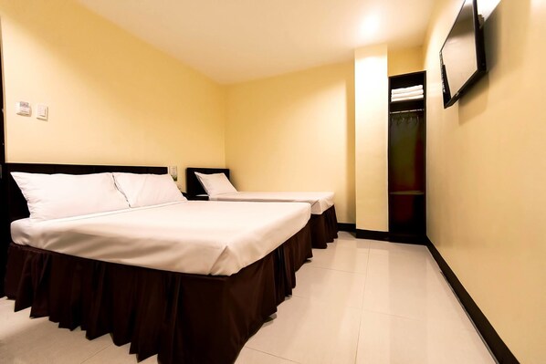 Habitación de hotel con dos camas, un armario y un espejo en la pared.