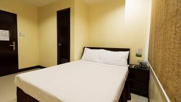 A hotel room with a bed, a nightstand, a door, and a wall with a textured pattern.