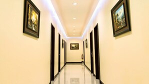 A hallway with framed artwork on the walls, recessed lighting, and a polished floor. - Winzelle Suites (Zamboanga)