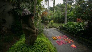 A garden pathway with a statue and flower arrangements. - Bucu Beji Ubud (Ubud)