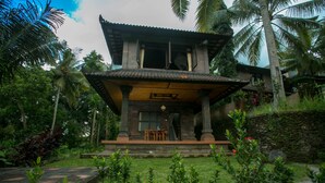 A traditional two-story building with a covered porch, surrounded by lush greenery and palm trees. - Bucu Beji Ubud (Ubud)