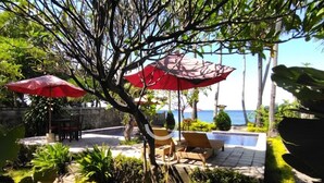 Un patio al aire libre con asientos y sombrillas, con vista a una masa de agua.