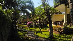 Un jardín con un sendero empedrado, palmeras y un edificio con balcón.