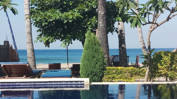 Zona de piscina con sillones de descanso, una piscina pequeña y vistas al mar.
