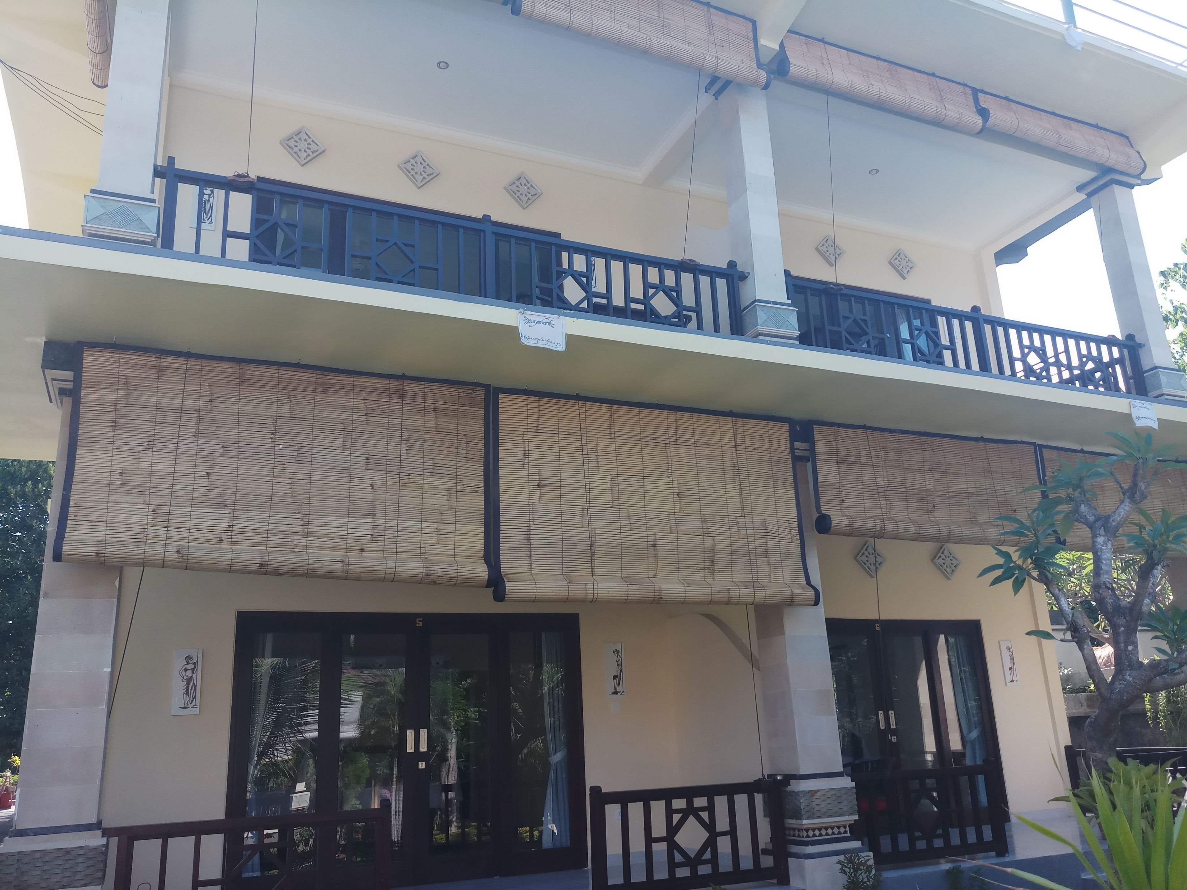 A two-story building with a balcony, large windows, and a covered entrance.
