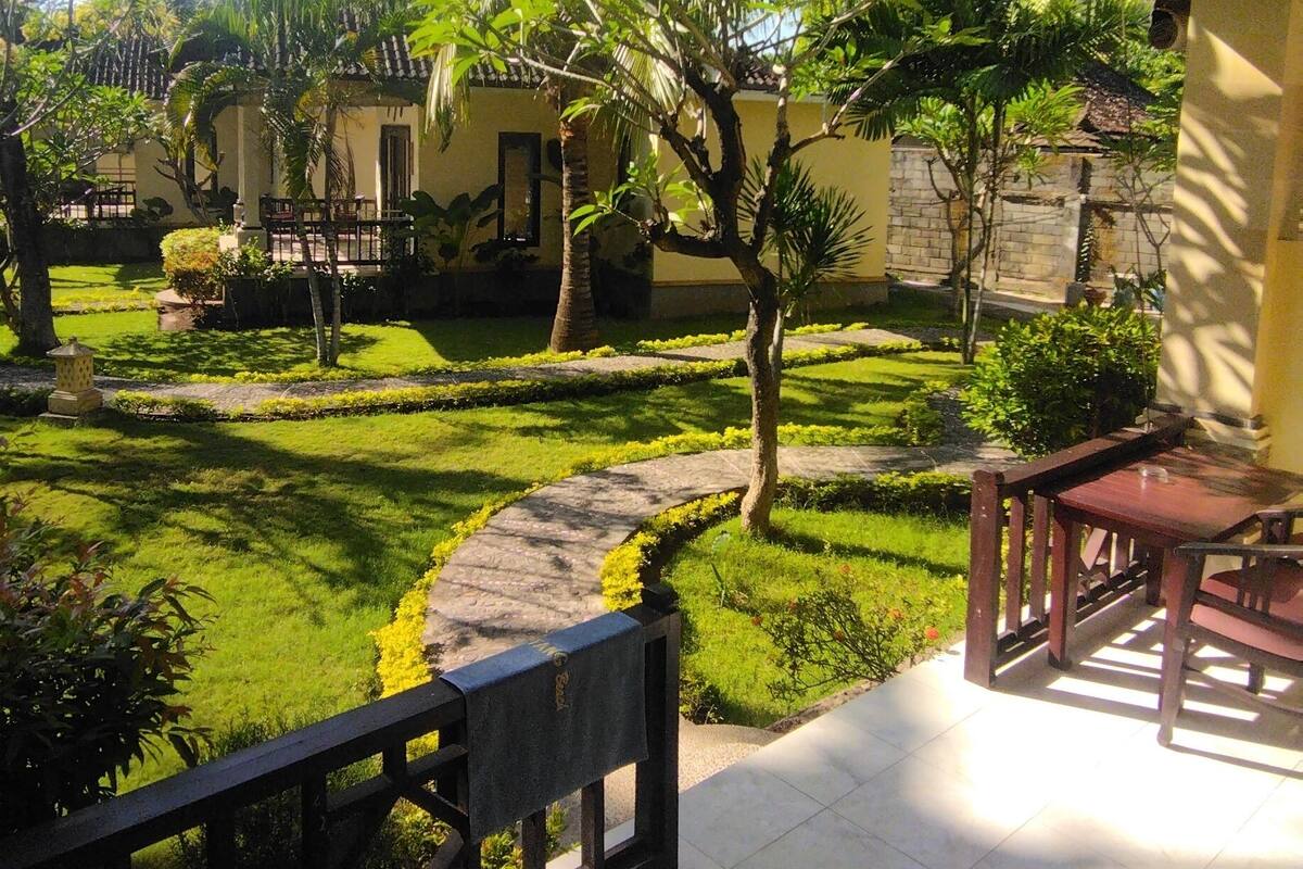 A courtyard with a tiled floor, a wooden bench, and a small tree.