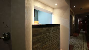 A hallway with a brick accent wall, recessed lighting, and a striped carpet.