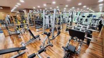 A gym with various exercise equipment, wooden flooring, and multiple ceiling lights.