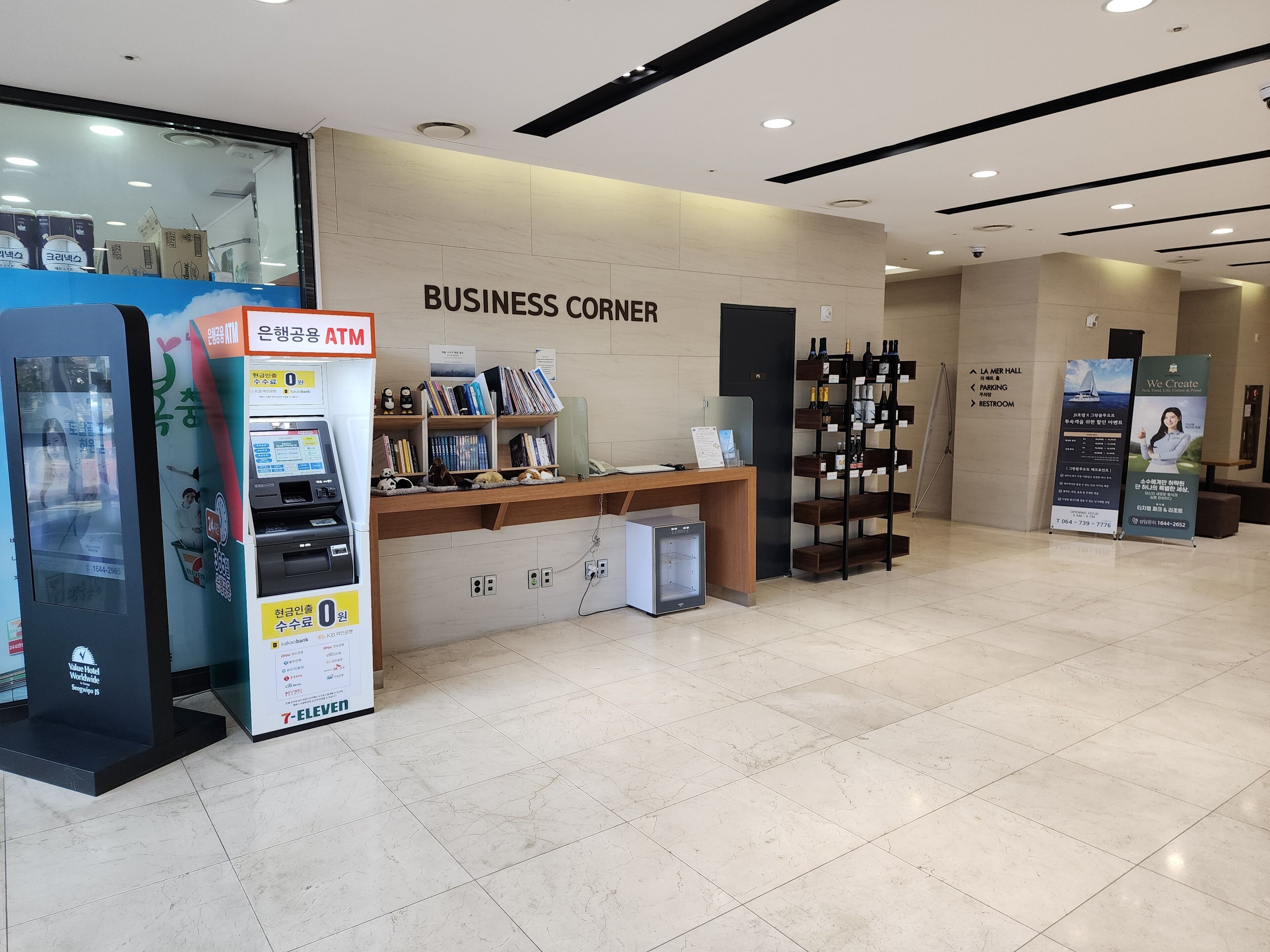 A business corner with an ATM, a reception desk, and a wine rack.