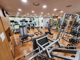 Un gimnasio con diversos equipos de ejercicio, incluyendo cintas de correr, máquinas de pesas y pesas libres.