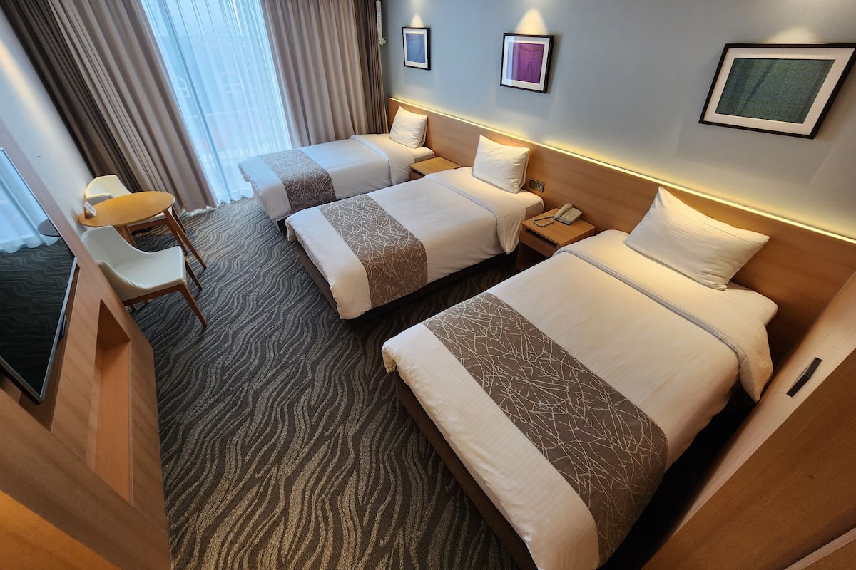 A hotel room with two beds, a desk, and a chair.