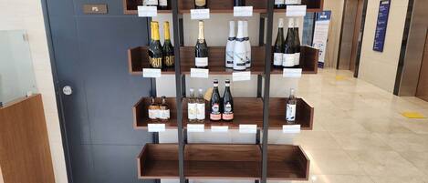 Verschillende wijnflessen staan op houten planken in een hotelhal.