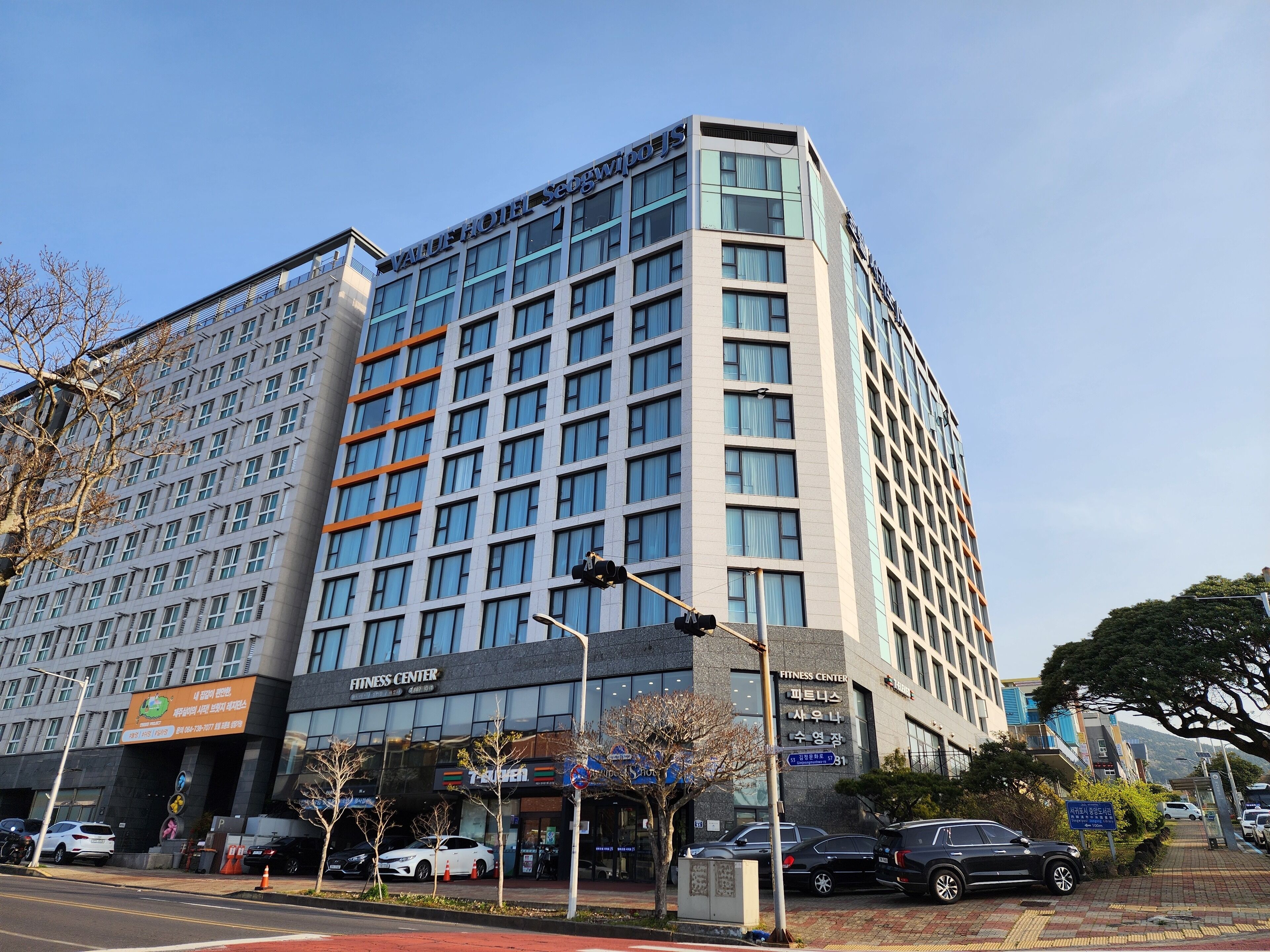 A modern hotel building with multiple floors, a fitness center, and a visible parking area.