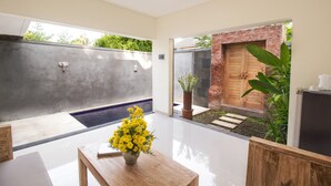 A modern interior with a wooden table, a potted plant, and a concrete wall. - Uma de Villa Sanur (Denpasar)