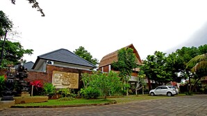 A residential area with brick houses, a paved driveway, and a parked car. - Uma de Villa Sanur (Denpasar)
