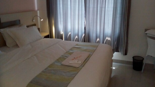 Une chambre d’hôtel avec un grand lit, une table de chevet avec une lampe et une fenêtre avec des rideaux.