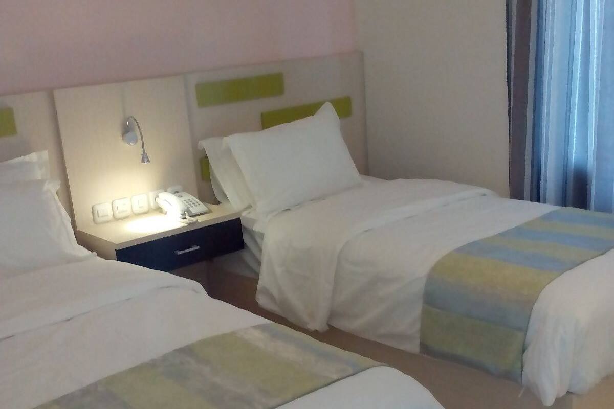 Ein Hotelzimmer mit zwei Betten, einem Nachttisch mit Telefon und einem Vorhangfenster.