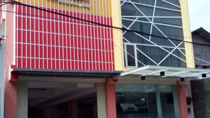 Un bâtiment à la façade rouge et jaune, doté d’une grande fenêtre en verre et d’une enseigne sur laquelle on peut lire le mot « Vision ».