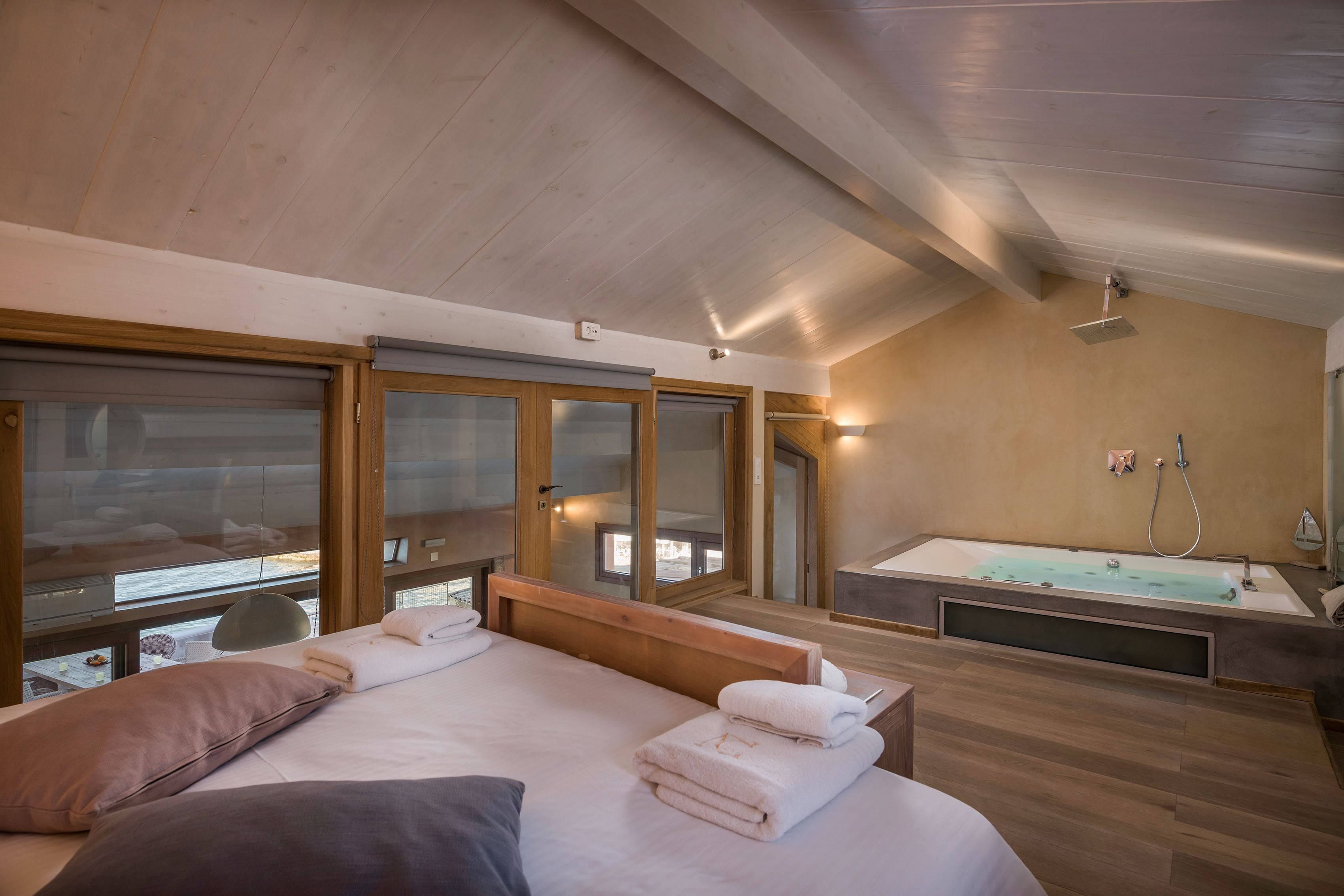 Una habitación de hotel moderna con una cama grande, una bañera y vistas al exterior.