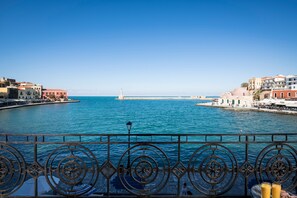 A coastal view with a clear sky, a lighthouse, and buildings along the waterfront. - Residenza Vranas Hotel (Chania)
