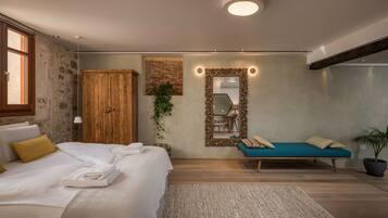 A bedroom with a bed, a sofa, a mirror, and a plant.