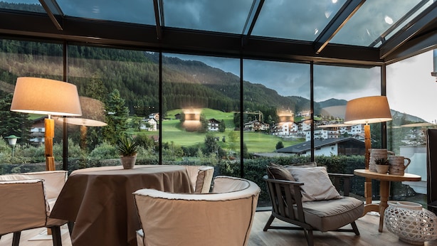 Un comedor moderno con grandes ventanales que ofrecen vistas panorámicas de un paisaje montañoso y un campo de golf.