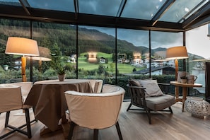 Un comedor moderno con grandes ventanales que ofrecen vistas panorámicas de un paisaje montañoso y un campo de golf.